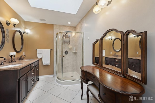 bathroom featuring tile patterned flooring, double vanity, a stall shower, and a sink