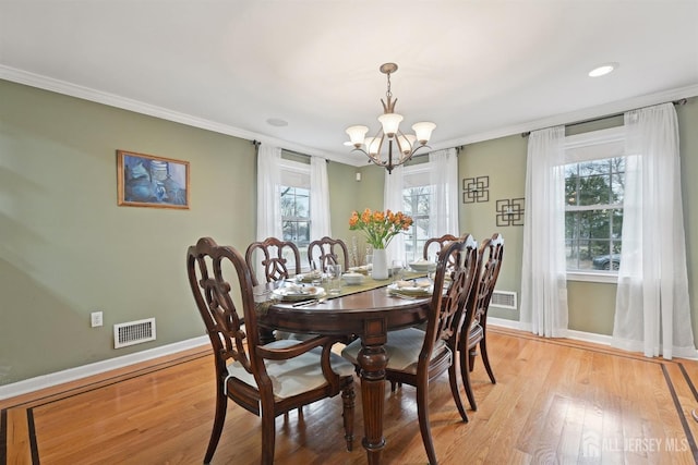 dining room with visible vents, a healthy amount of sunlight, light wood-type flooring, and ornamental molding