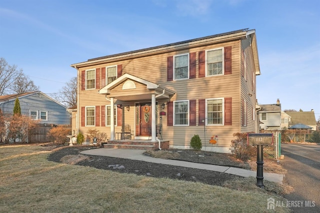 colonial-style house featuring a front yard and fence