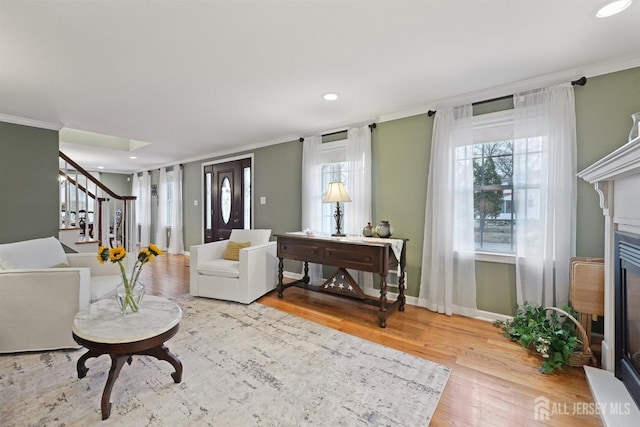 living room with crown molding, baseboards, stairway, a fireplace, and wood finished floors