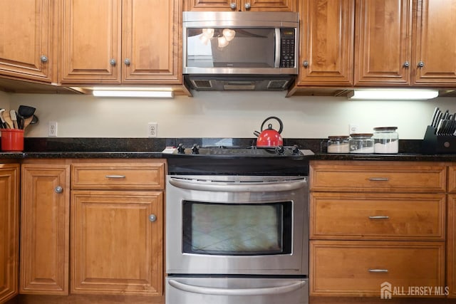 kitchen featuring dark stone countertops, brown cabinets, and stainless steel appliances