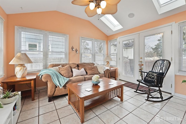 living room with light tile patterned floors, french doors, lofted ceiling with skylight, and a ceiling fan