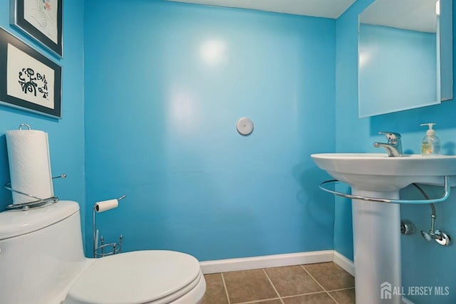 half bathroom featuring tile patterned floors, toilet, and baseboards