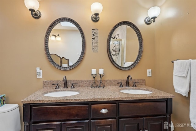 bathroom with a sink, toilet, and double vanity