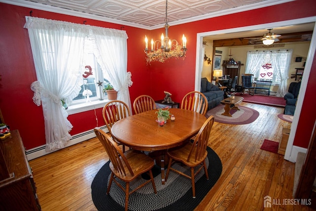 dining room featuring ceiling fan with notable chandelier, wood-type flooring, ornamental molding, and baseboard heating