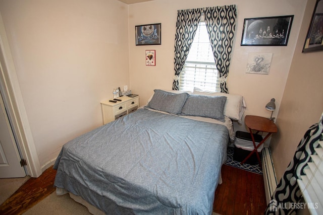 bedroom featuring hardwood / wood-style flooring and a baseboard heating unit