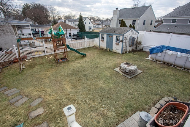 view of yard with a playground, a covered pool, a shed, and an outdoor fire pit