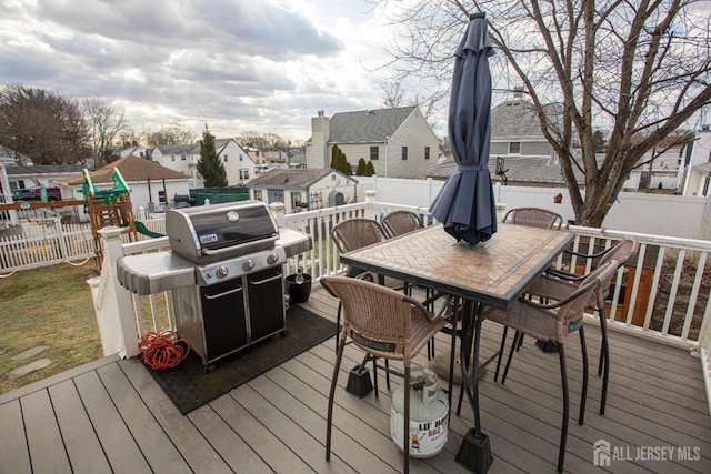 wooden deck featuring area for grilling and a playground