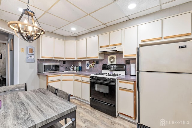 164 Holly St, Port Reading, NJ 07064 - kitchen featuring freestanding refrigerator, gas range oven, under cabinet range hood, stainless steel microwave, and a chandelier