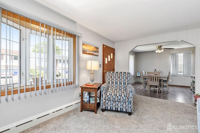 164 Holly St, Port Reading, NJ 07064 - living area with a baseboard radiator, a ceiling fan, carpet flooring, arched walkways, and wood finished floors