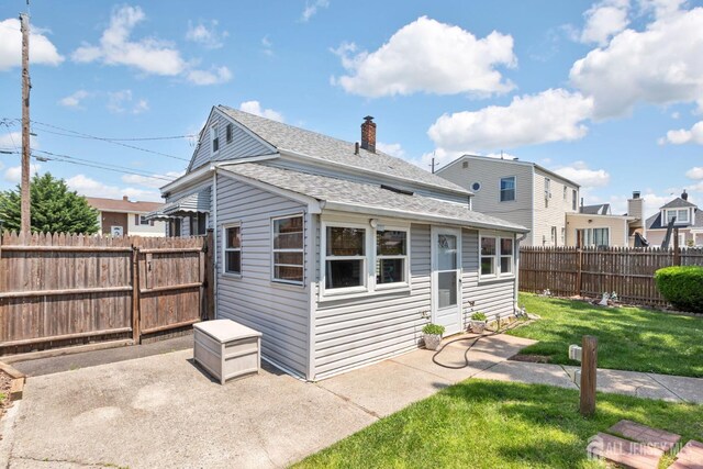 164 Holly St, Port Reading, NJ 07064 - back of property featuring a patio area, a fenced backyard, a shingled roof, and a chimney