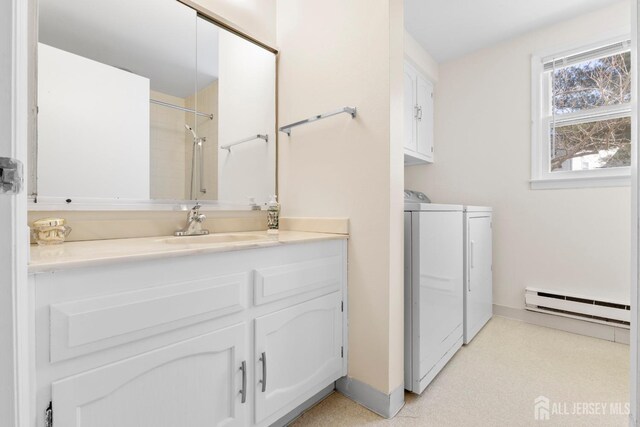 full bathroom featuring vanity, baseboards, a shower, baseboard heating, and washing machine and clothes dryer