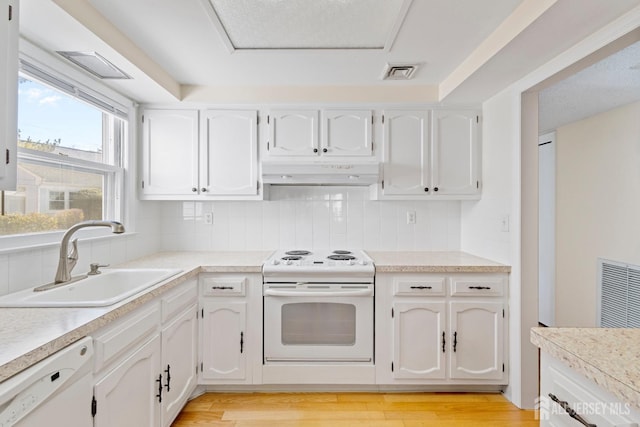 kitchen featuring under cabinet range hood, white appliances, a sink, white cabinetry, and visible vents