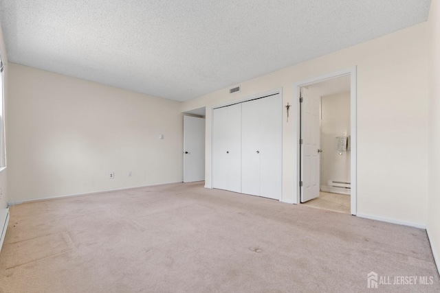 unfurnished bedroom featuring a textured ceiling, carpet floors, a closet, and visible vents