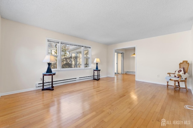 unfurnished room featuring a baseboard radiator, baseboard heating, light wood-style floors, a textured ceiling, and baseboards