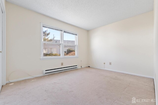 carpeted spare room featuring baseboards, baseboard heating, and a textured ceiling