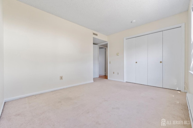 unfurnished bedroom featuring a textured ceiling, carpet flooring, visible vents, baseboards, and a closet