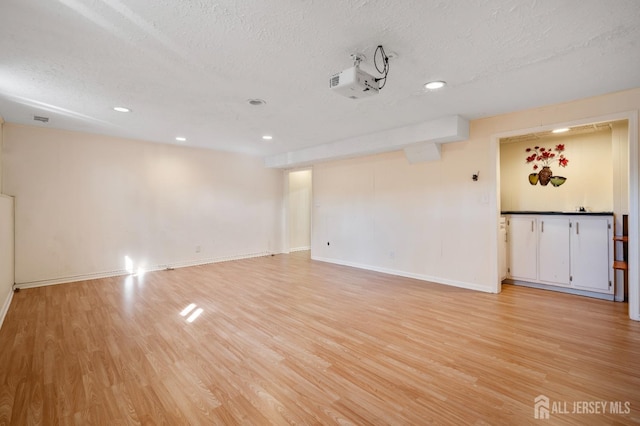 unfurnished room featuring a textured ceiling, light wood-style flooring, baseboards, and recessed lighting