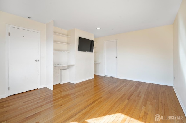 unfurnished living room with light wood-style flooring, baseboards, built in features, and recessed lighting
