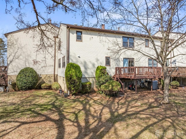 back of property with a wooden deck, central AC, a yard, and a chimney