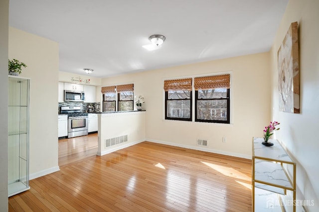 unfurnished living room with light wood-type flooring and baseboards