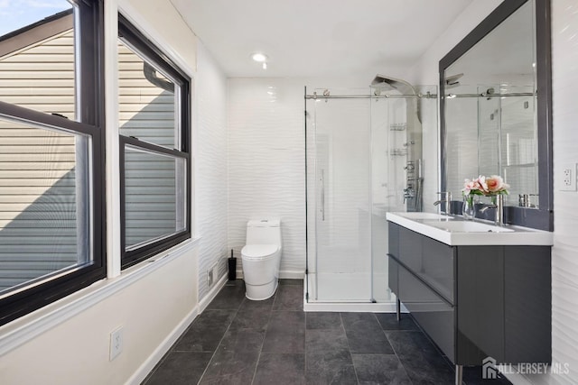 bathroom with a shower stall, toilet, vanity, and baseboards