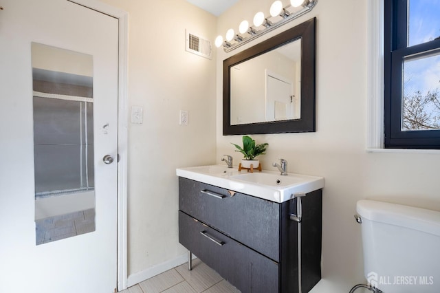 full bathroom featuring a shower with door, toilet, and double vanity