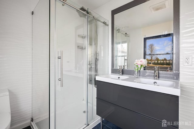 full bathroom with a shower stall and double vanity