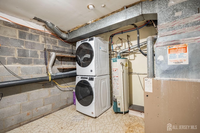 clothes washing area featuring stacked washer / drying machine, gas water heater, and concrete block wall