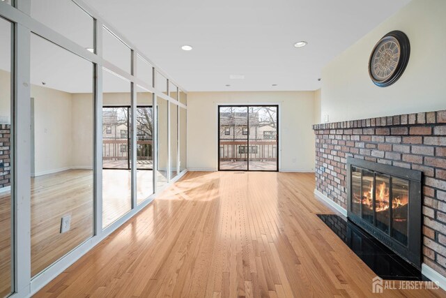 unfurnished living room with a fireplace, baseboards, light wood-style flooring, and recessed lighting