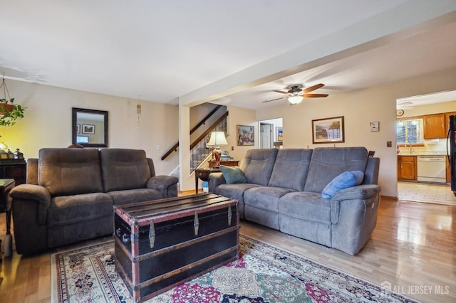 living room featuring ceiling fan, light wood-type flooring, and sink