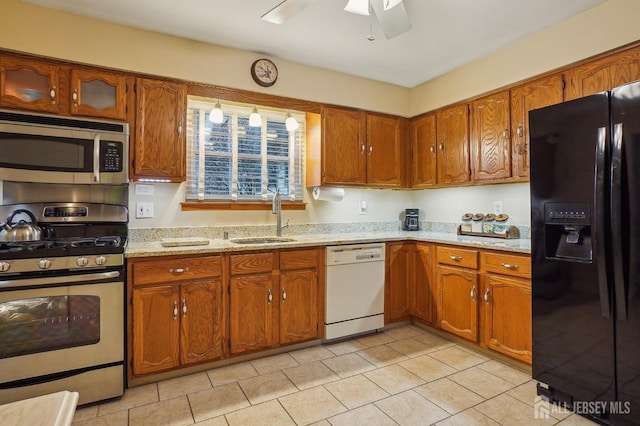 kitchen featuring stainless steel appliances, sink, ceiling fan, and light stone counters