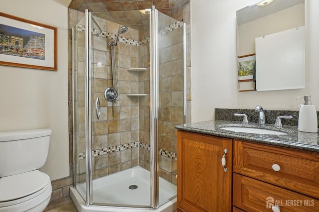 bathroom featuring toilet, a shower with door, vanity, and tile patterned floors