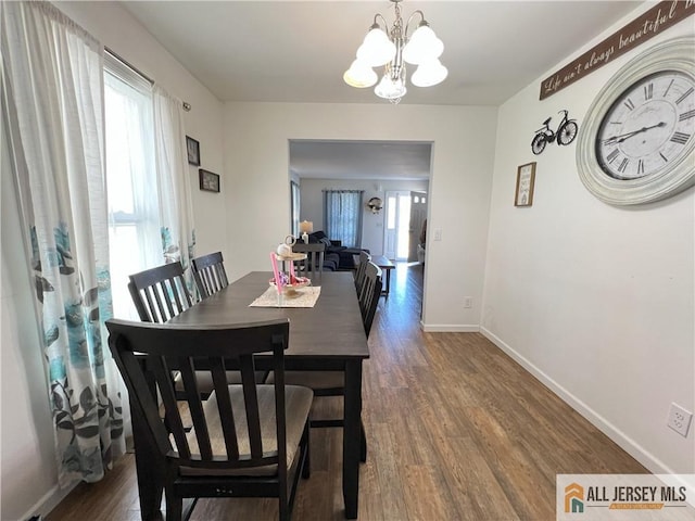 dining area with a chandelier, baseboards, and wood finished floors