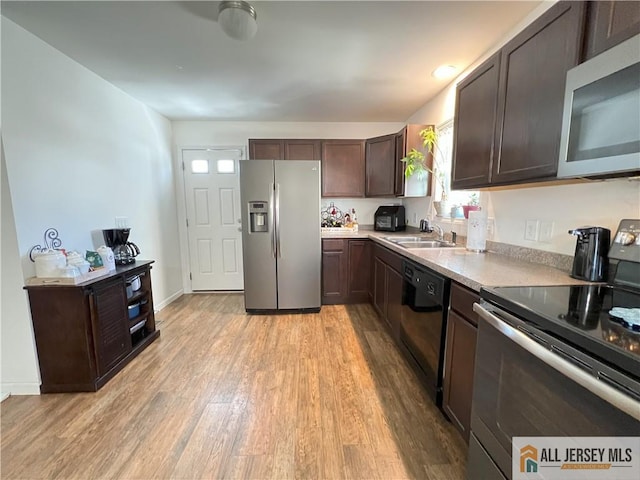 kitchen featuring a sink, light countertops, dark brown cabinets, light wood-style floors, and appliances with stainless steel finishes