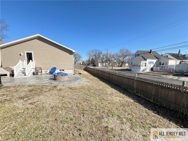 view of yard featuring a patio, fence, and a residential view