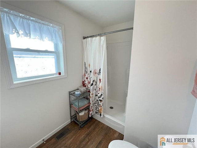 full bathroom featuring visible vents, baseboards, wood finished floors, and a shower stall