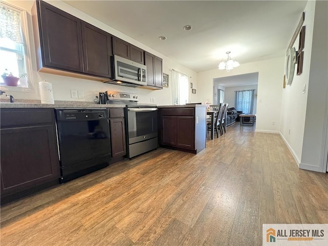 kitchen with dark brown cabinetry, a notable chandelier, light wood-type flooring, and stainless steel appliances