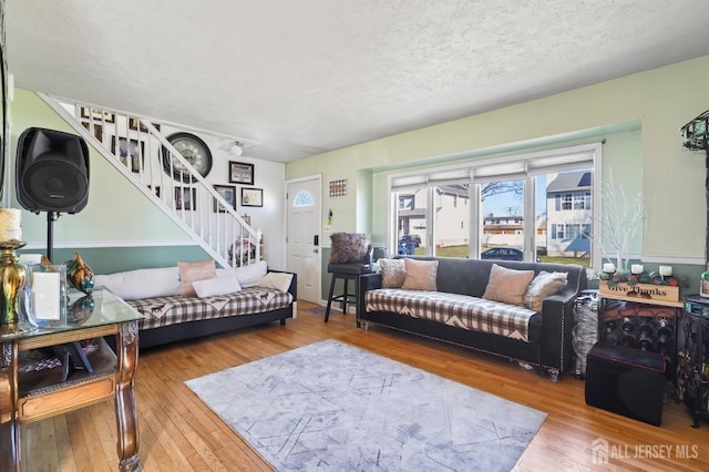 living room with stairway, hardwood / wood-style flooring, and a textured ceiling