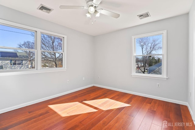 spare room featuring baseboards, wood-type flooring, and a ceiling fan