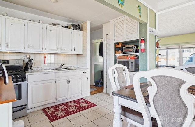 kitchen with stainless steel appliances, white cabinets, a sink, and light countertops
