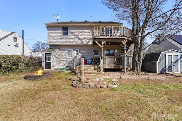 rear view of house featuring an outdoor fire pit, a deck, a storage unit, and a lawn