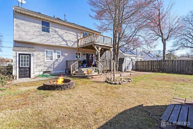 rear view of property featuring an outdoor fire pit, a storage unit, a deck, and an outdoor structure