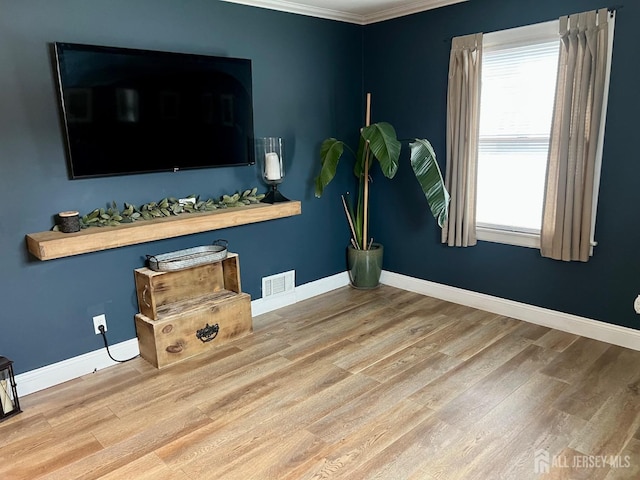 interior space with wood finished floors, visible vents, ornamental molding, and baseboards