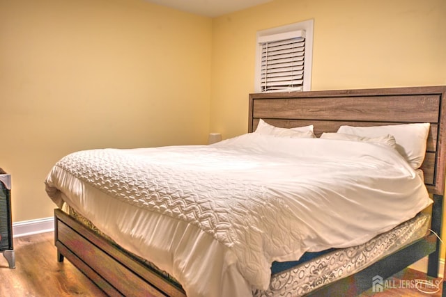 bedroom with wood finished floors and baseboards