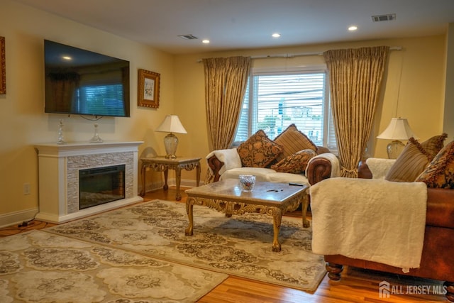 living room with wood finished floors, baseboards, recessed lighting, and a stone fireplace