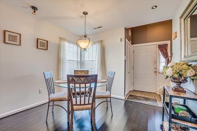 dining space with dark wood-style floors, visible vents, and baseboards