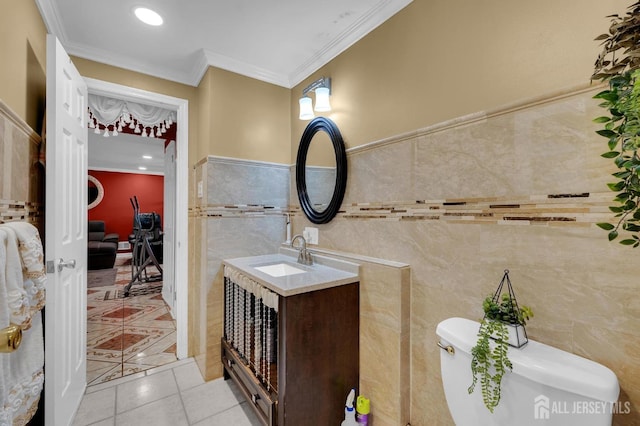 bathroom featuring tile patterned floors, vanity, crown molding, tile walls, and toilet