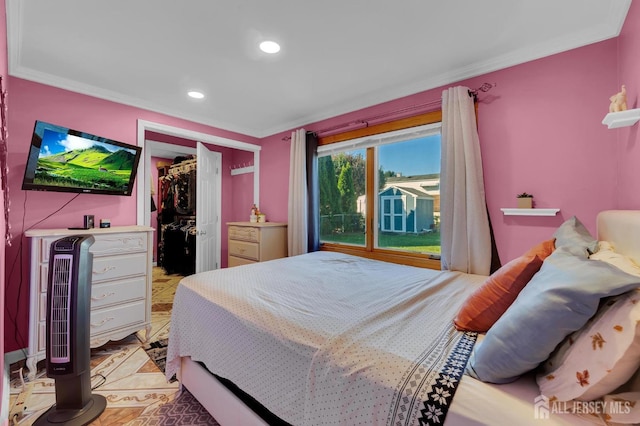 bedroom with a walk in closet, a closet, and ornamental molding