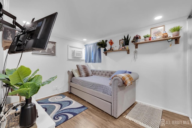 living room with light hardwood / wood-style floors, an AC wall unit, and crown molding